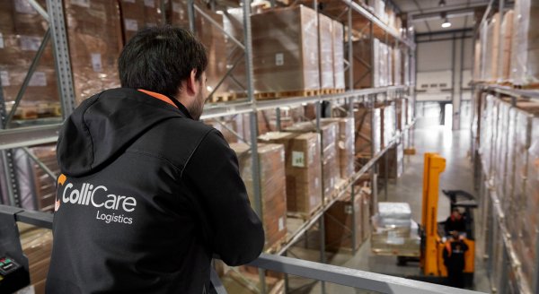 An employee in branded ColliCare clothes looking over the storage and the goods being placed in the shelves